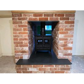 Double sided stove in a brick fireplace with oak beam and slate hearth